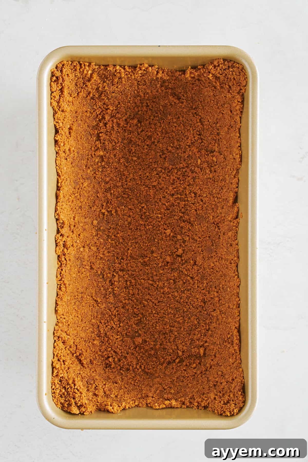 Biscoff cookie crust pressed into a loaf pan.