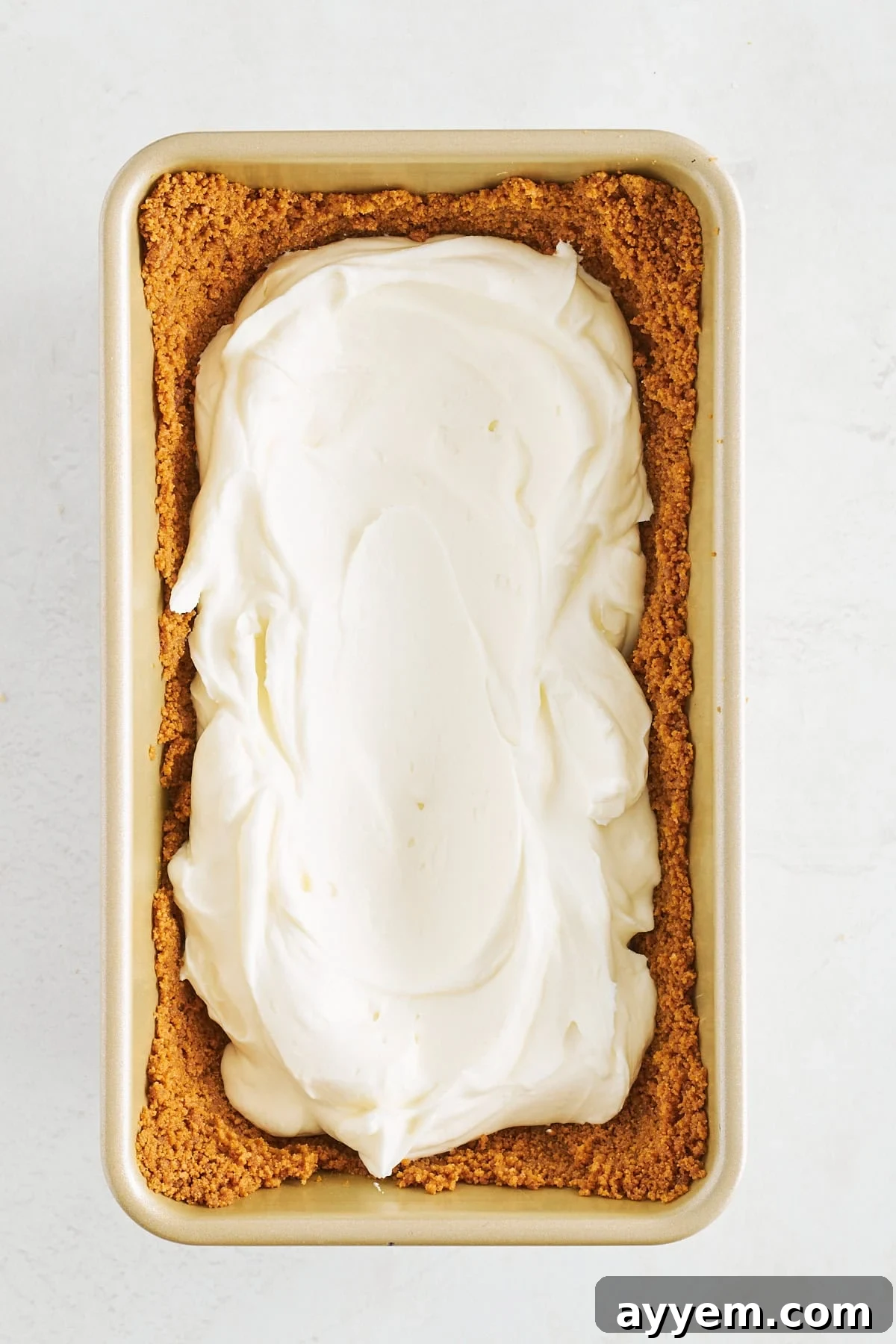 Cheesecake filling pressed into a Biscoff cookie crust in a loaf pan.