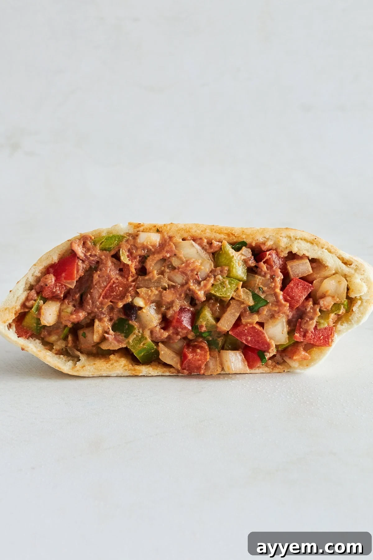 An unbaked hawawshi pita pocket, showing the generous filling inside.