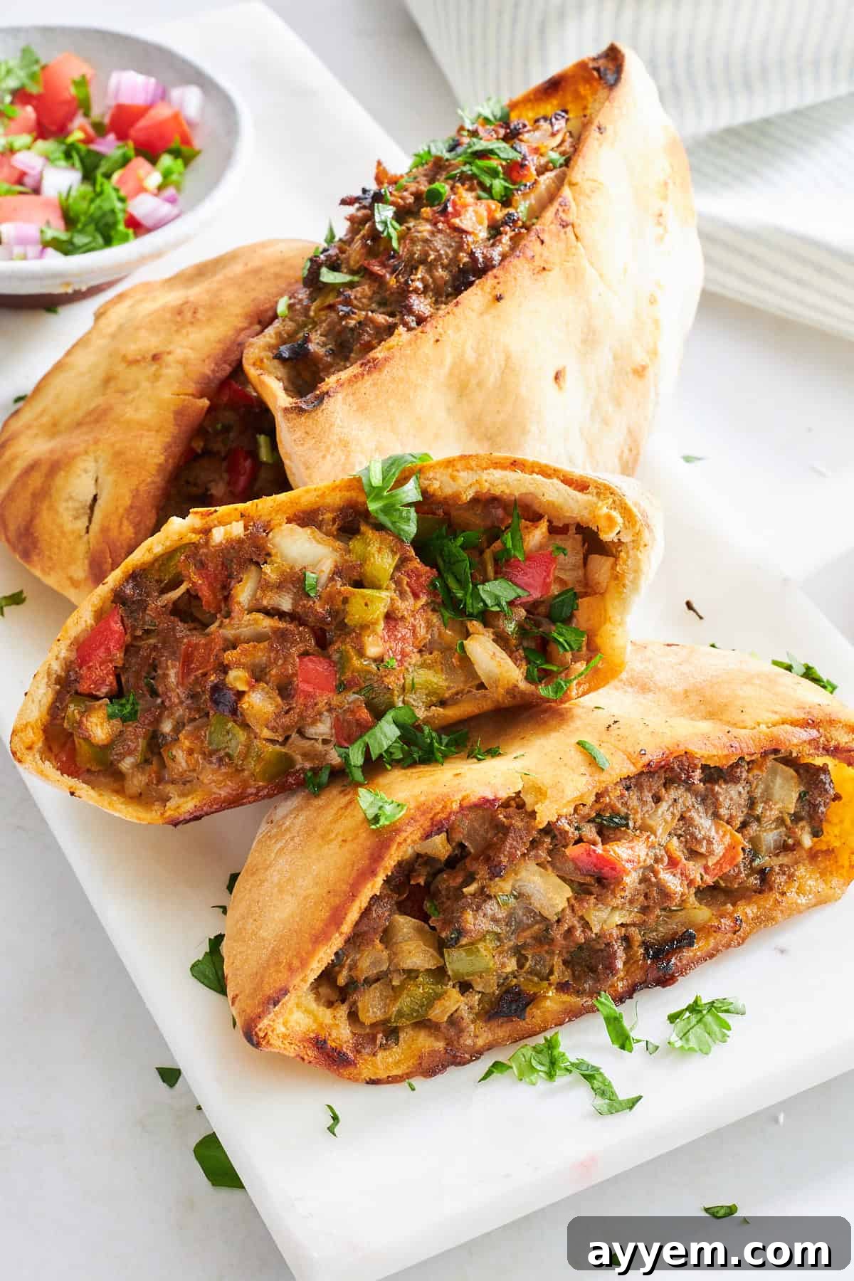 Four baked veggie-packed hawawshi pita halves on a plate, ready to serve.