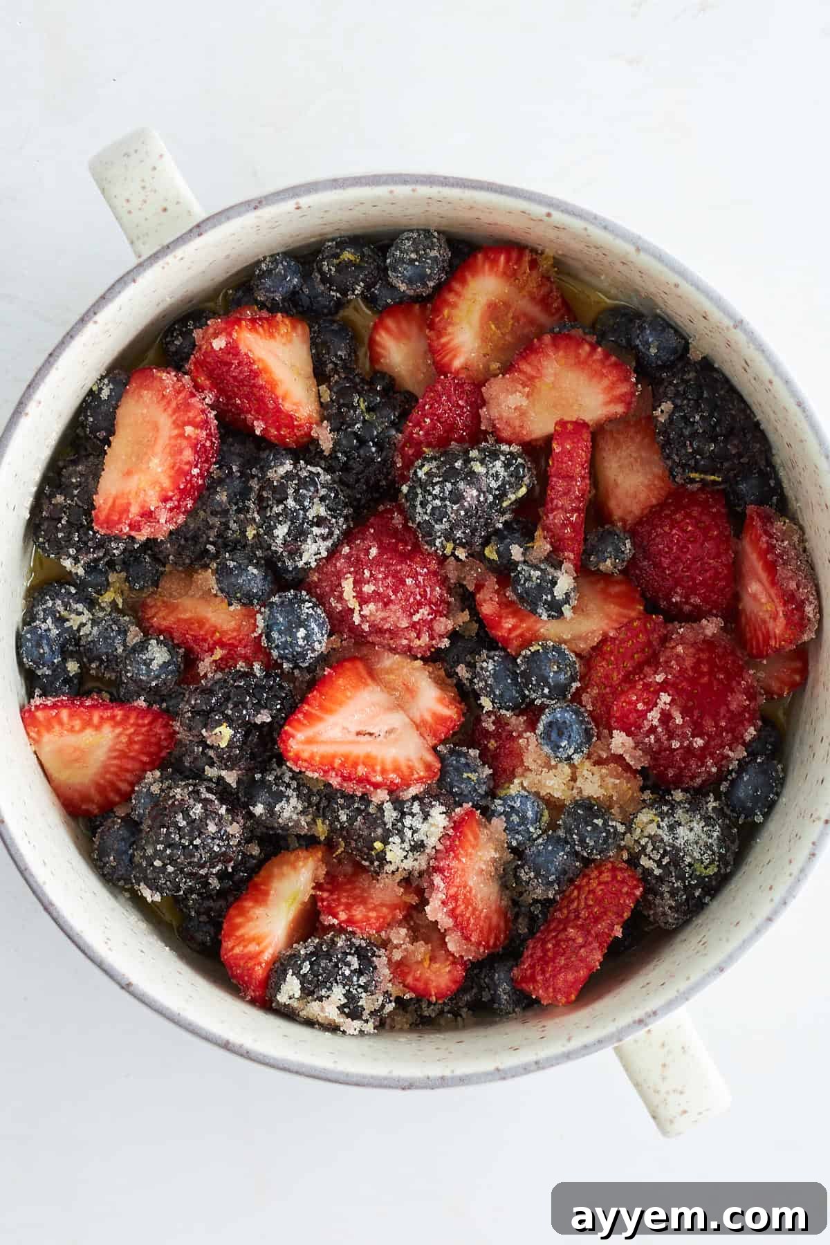 Mixed berry filling with vibrant blueberries, strawberries, raspberries, and blackberries, lightly coated in sugar and lemon zest, ready for baking.