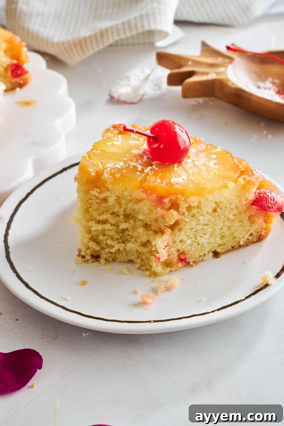 A slice of pineapple upside down cake on a plate with a bite missing. 