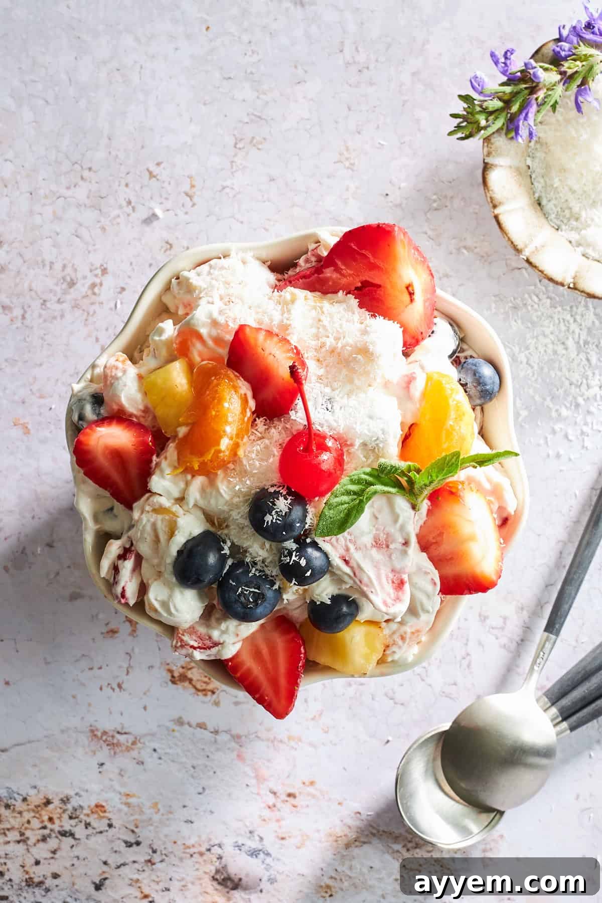 An overhead shot showcasing a beautifully mixed bowl of Ambrosia fruit salad, highlighting its creamy texture and colorful fruit medley.