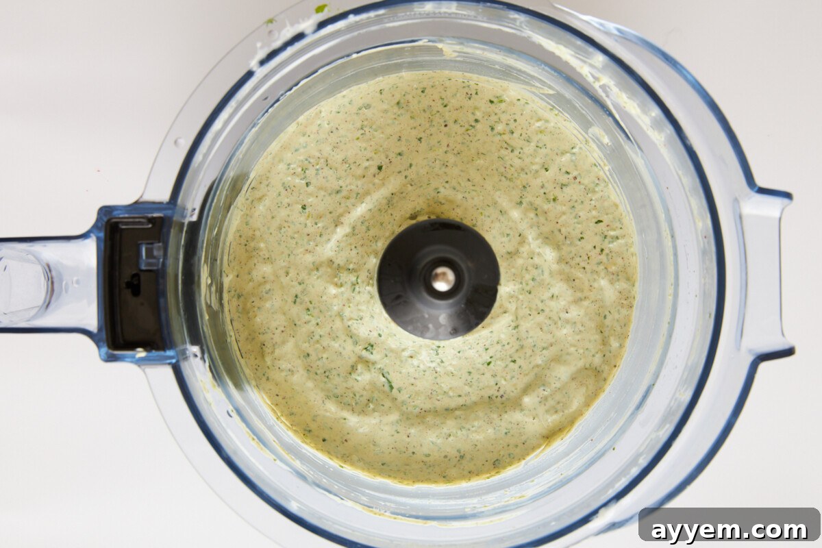 Coleslaw dressing in a food processor, appearing creamy and smooth.
