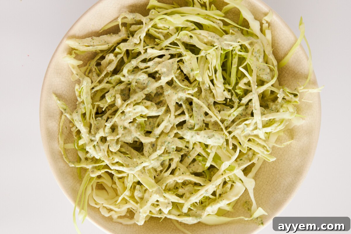 Homemade cabbage slaw in a mixing bowl, freshly mixed with dressing.