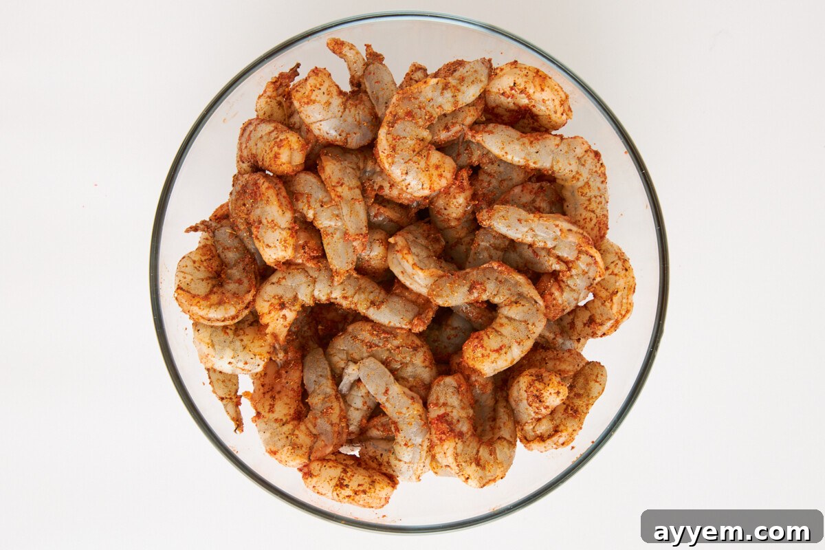Raw seasoned shrimp in a mixing bowl, ready for cooking.