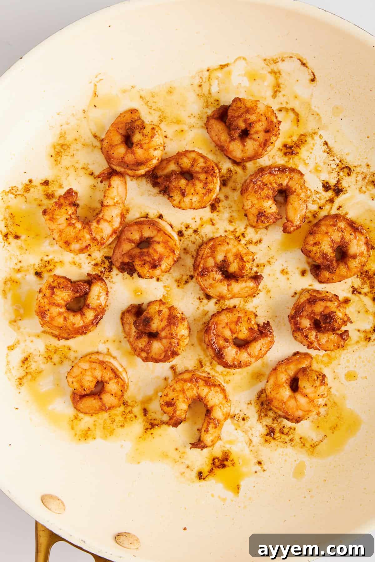 Close-up of blackened shrimp cooking in a hot skillet, showing the perfectly seared crust.