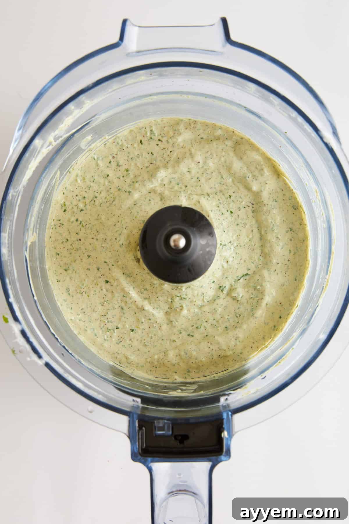 Coleslaw dressing being blended in a food processor, appearing creamy and smooth.