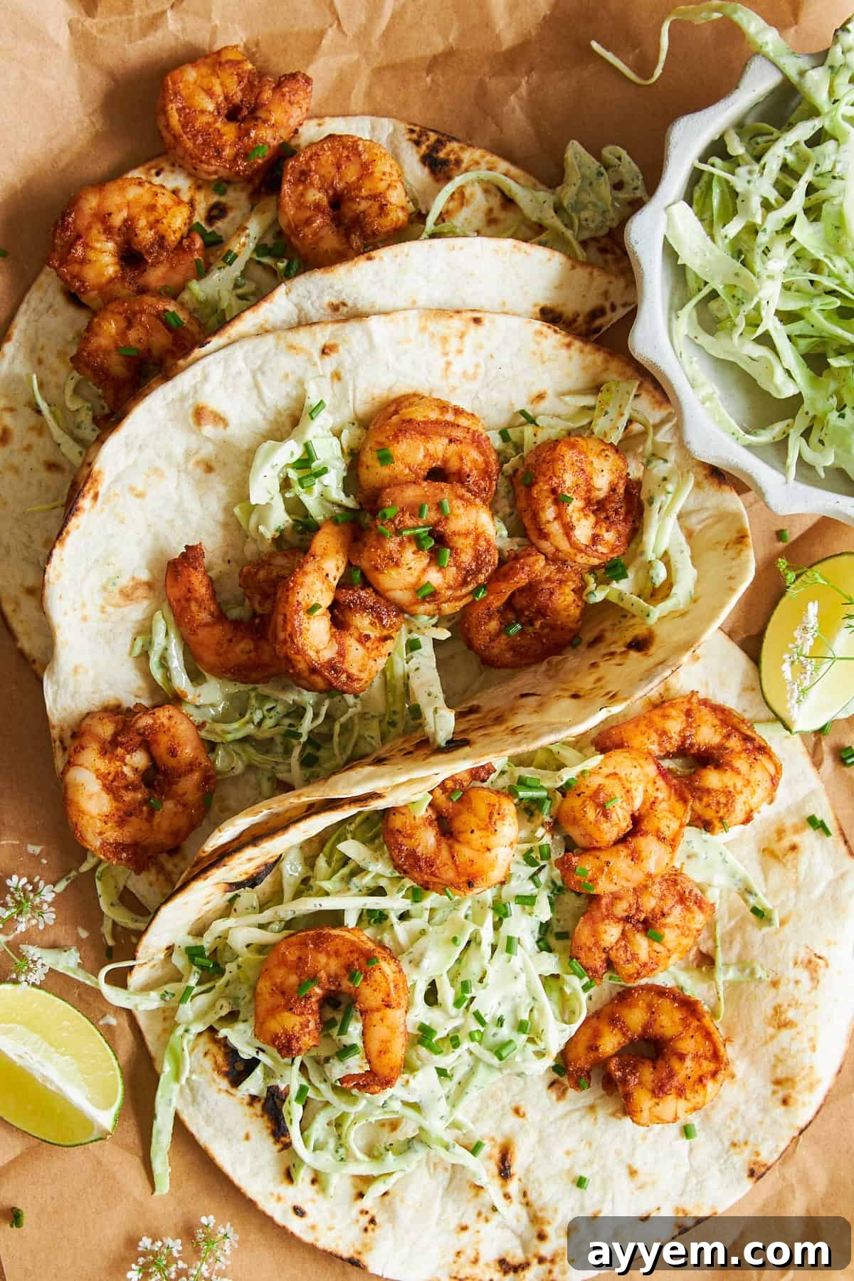 A close-up of three completed blackened shrimp tacos, beautifully presented with vibrant slaw and perfectly cooked shrimp.