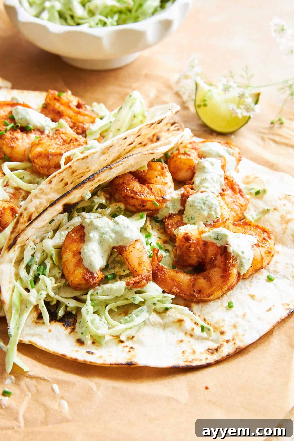 Close-up of a single blackened shrimp taco held in hand, showing off the textures and colors.