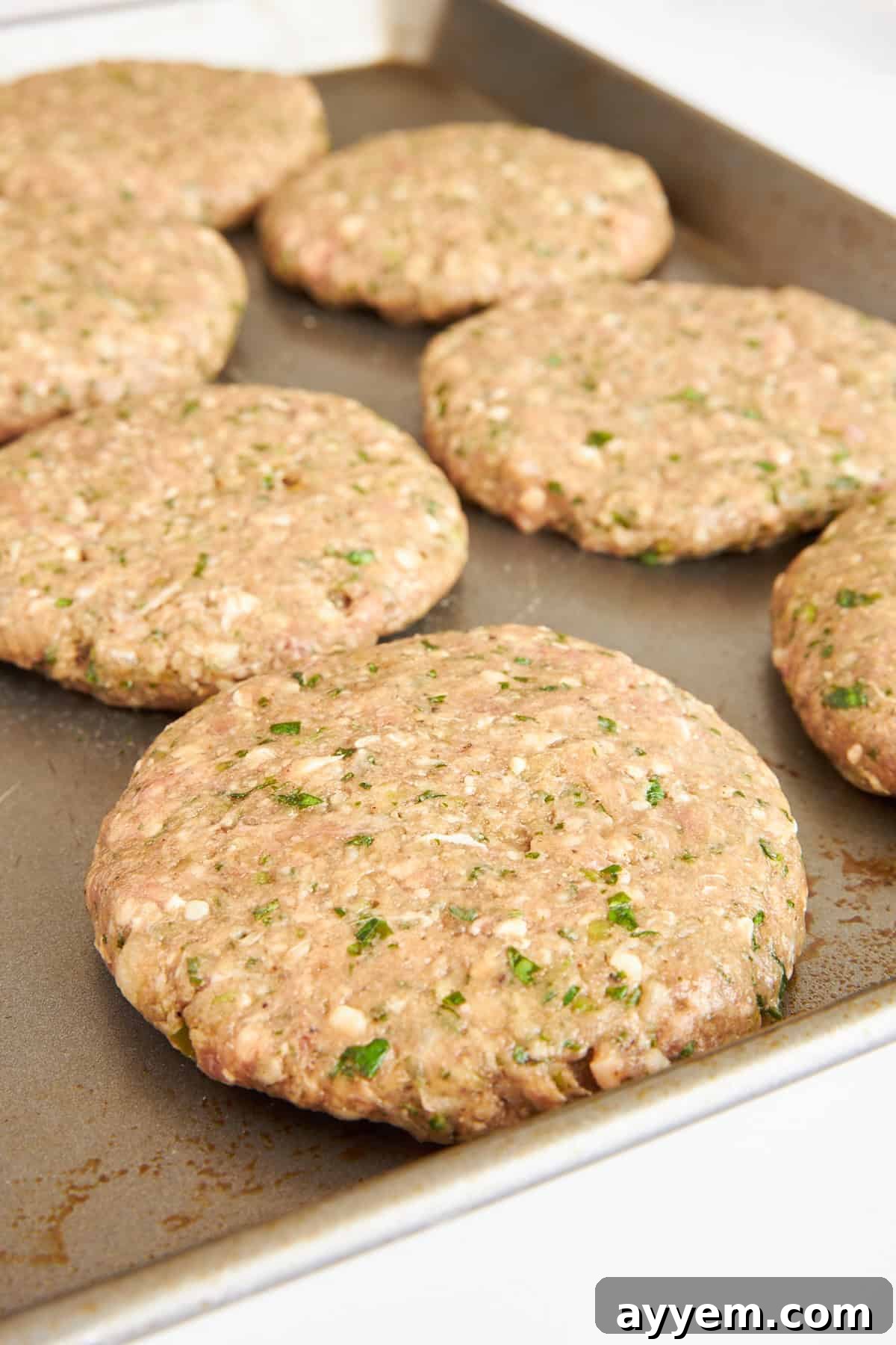 Freshly formed lamb kofta burger patties arranged neatly on a baking sheet, ready for cooking.