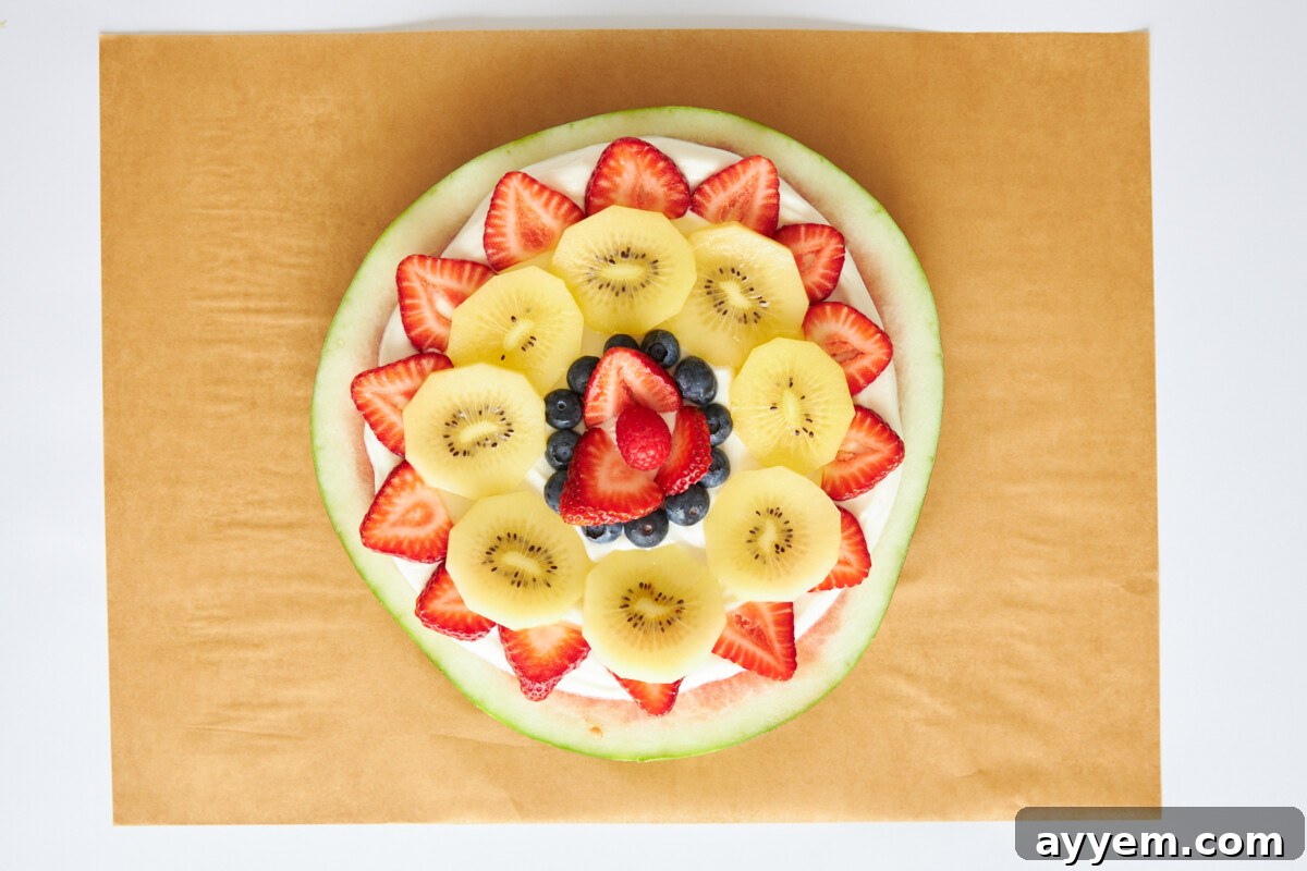 Watermelon fruit pizza decorated with colorful berries and kiwi slices.