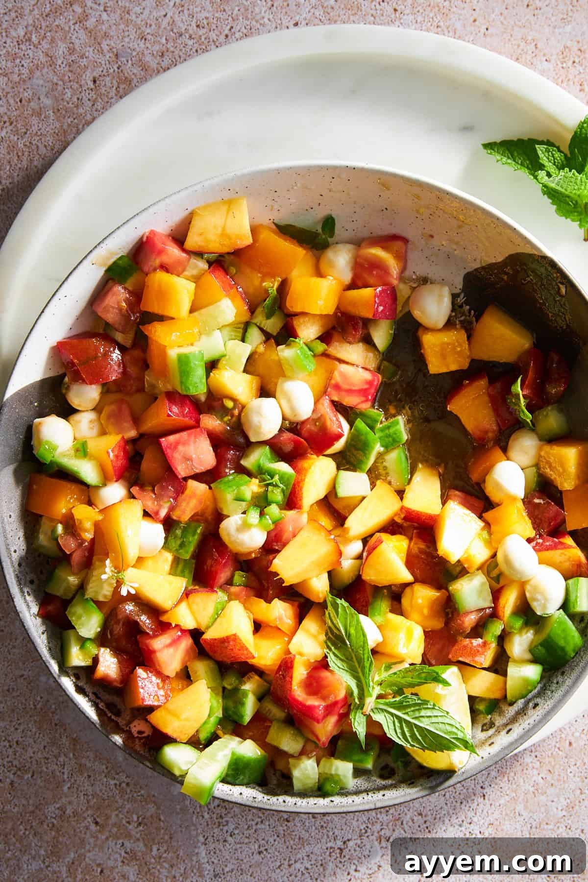 A close-up shot of the vibrant peach salad with mozzarella pearls, highlighting the fresh ingredients and the sweet and savory balance.