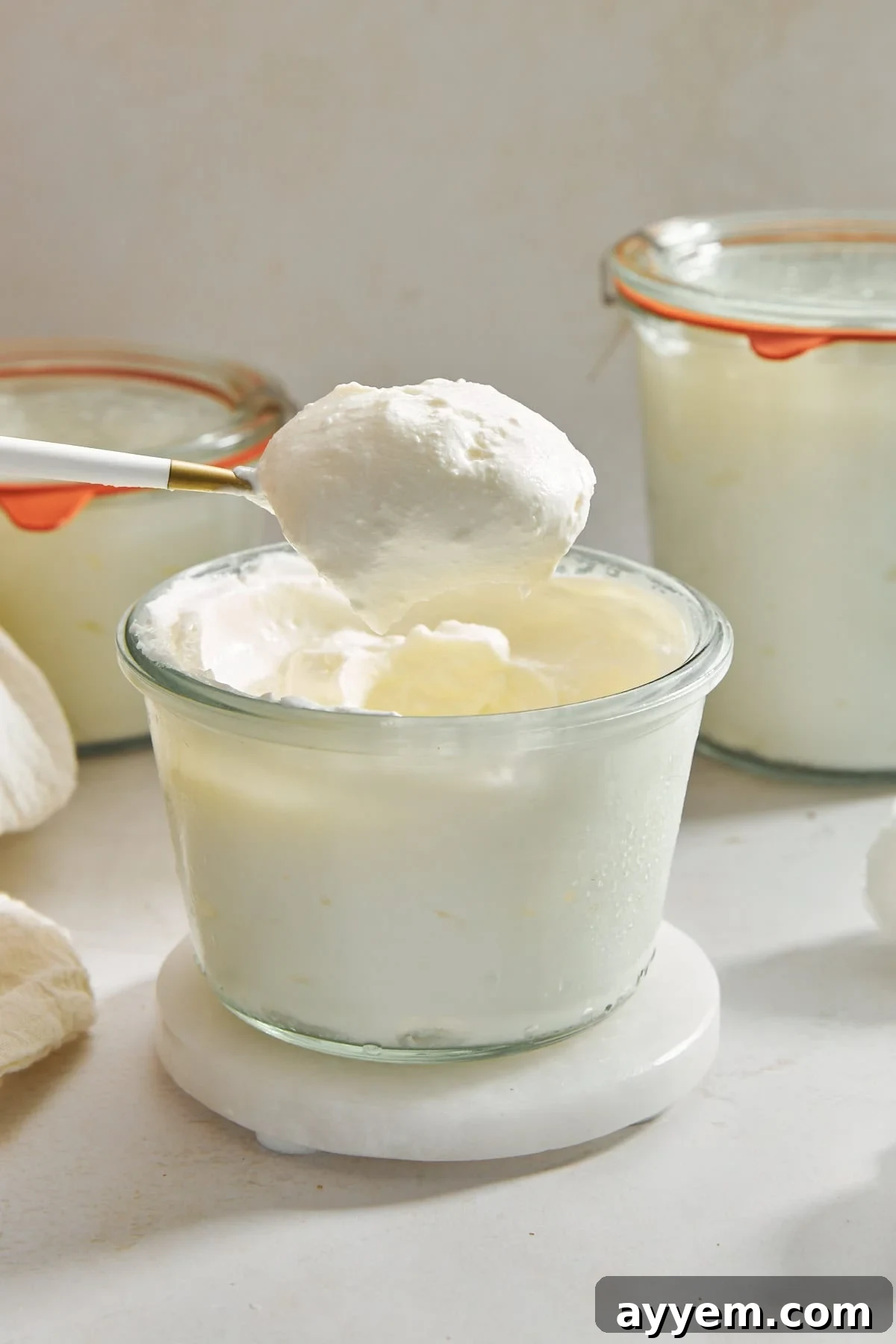 Three jars of homemade Greek yogurt, stacked and ready to be enjoyed or customized.