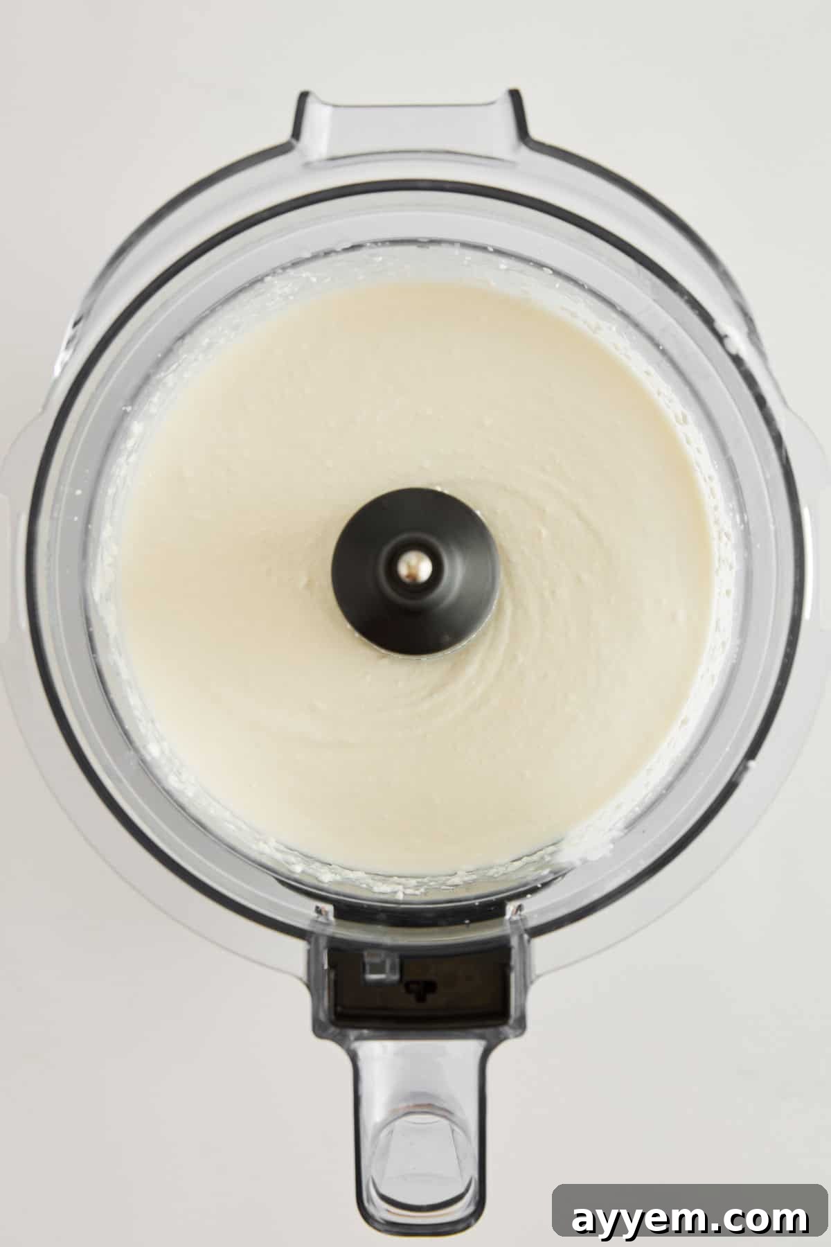 The smooth, airy texture of whipped cottage cheese in a food processor bowl, showcasing the transformation of the ingredients into a luscious base.