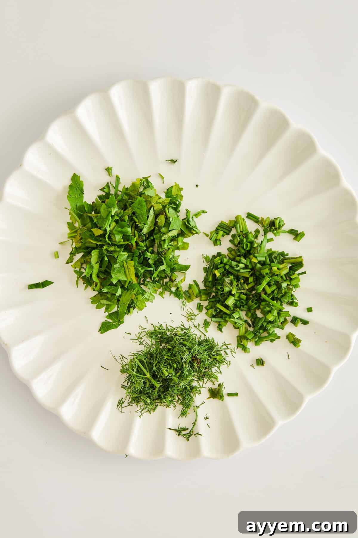 A selection of freshly chopped herbs, including dill, chives, and parsley, essential for adding bright, aromatic notes to the labneh dressing.