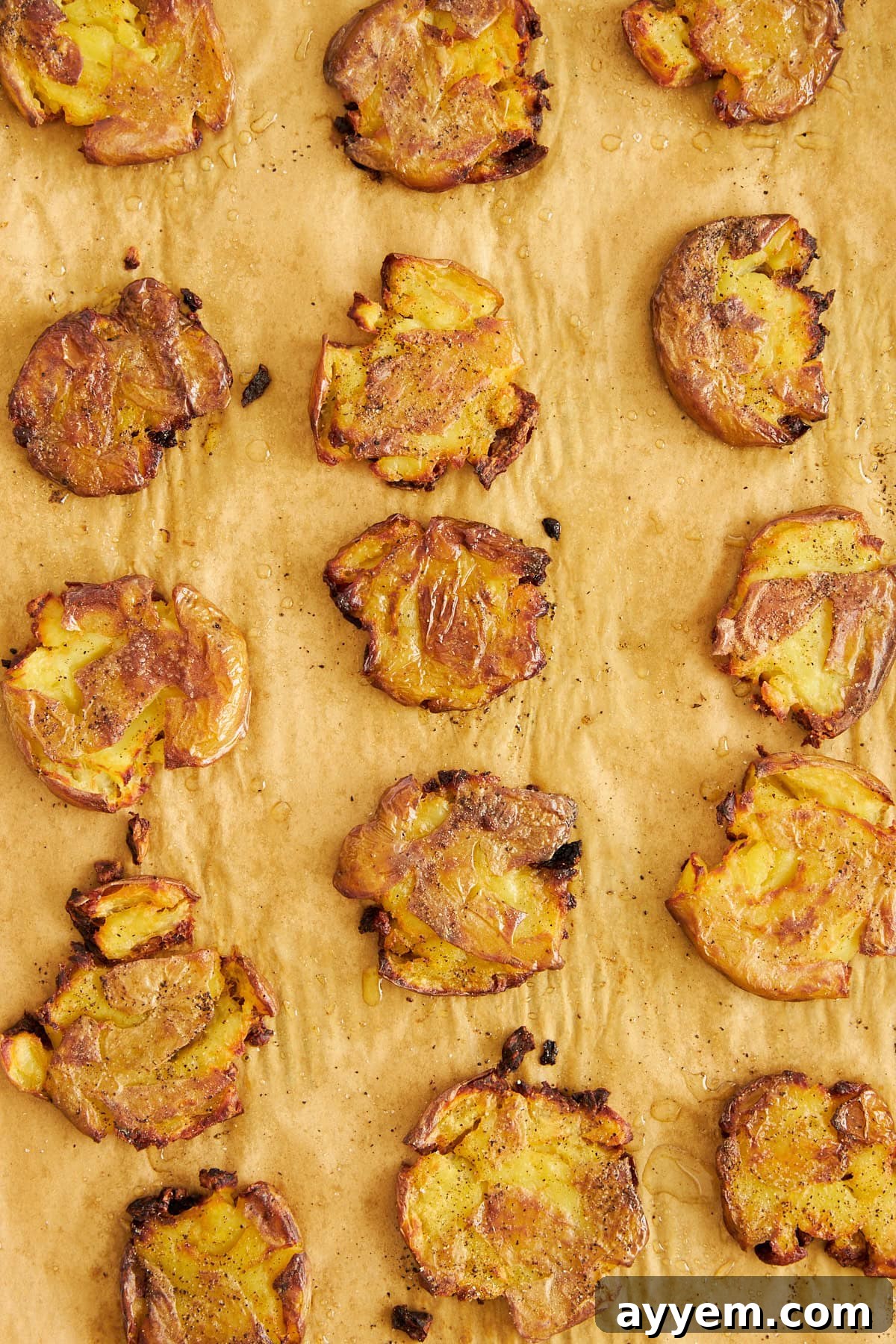 Perfectly baked crispy potatoes, golden brown and glistening, cooling on a parchment-lined baking sheet, ready to be combined with the labneh dressing.