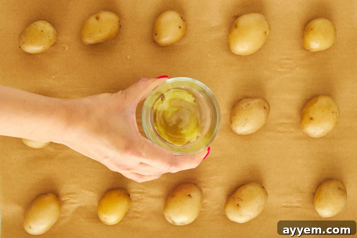 A cup flattening potatoes on a baking sheet.