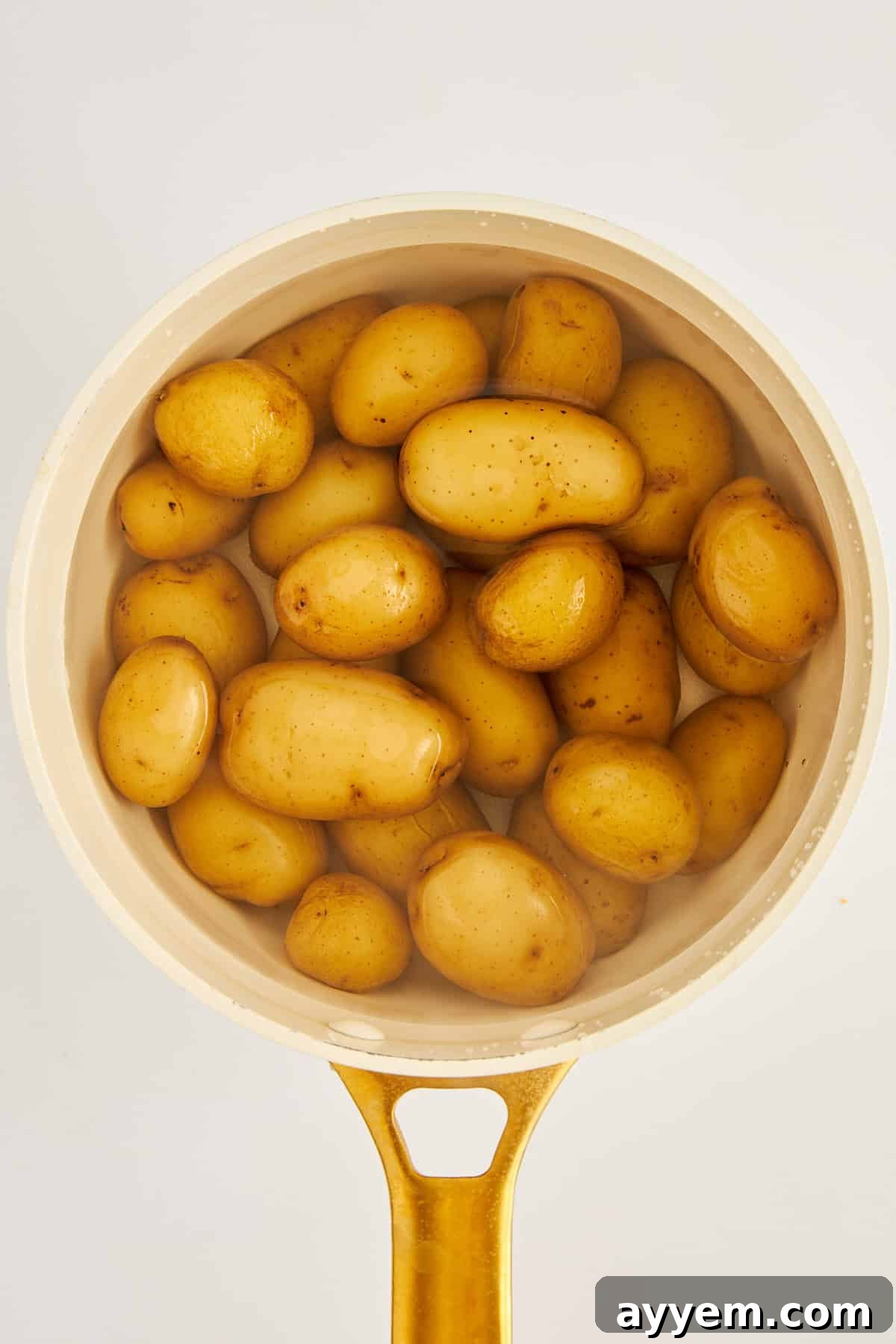Potatoes boiling in a large pot on the stove.