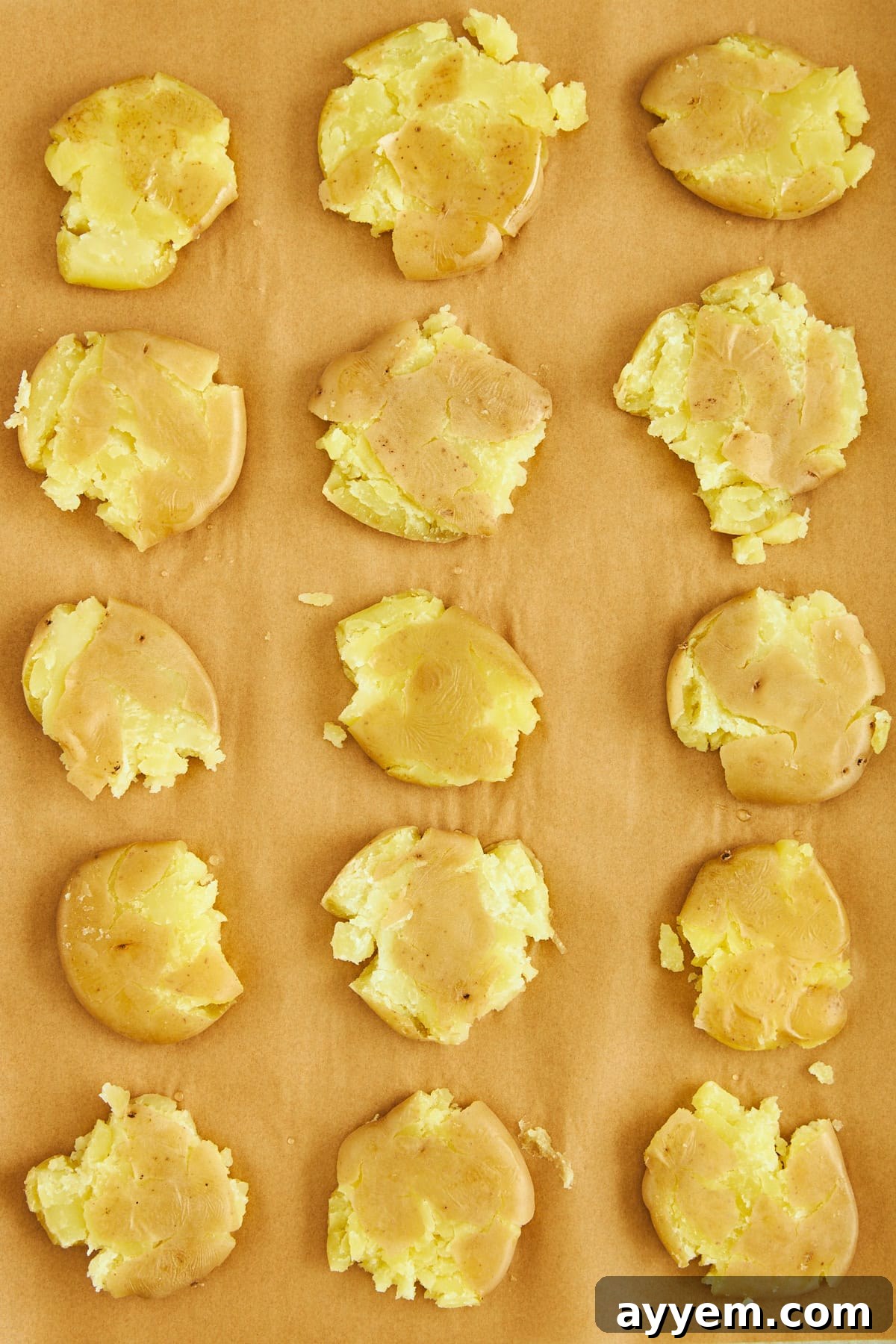 A baking sheet filled with perfectly smashed boiled potatoes, evenly spaced.