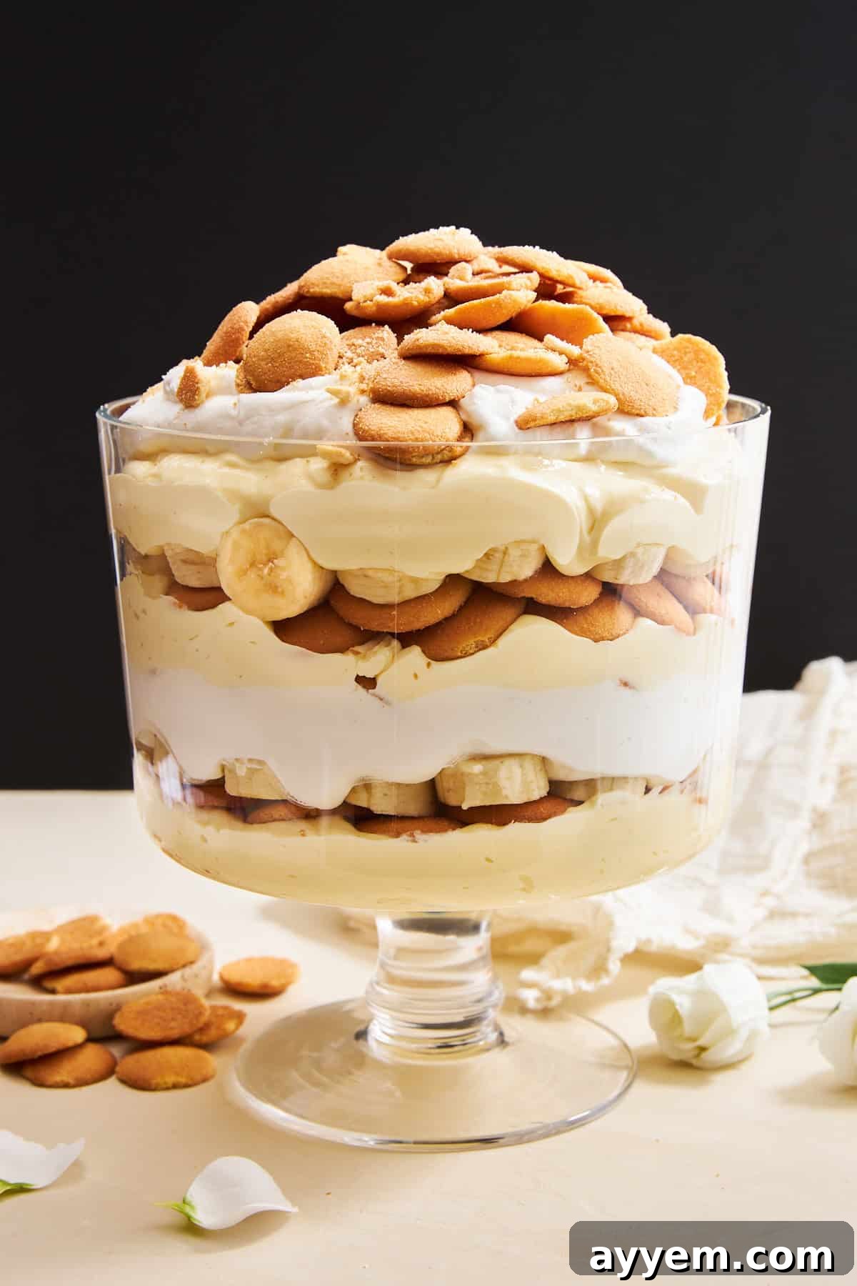A beautiful trifle bowl filled with layers of homemade easy banana pudding, garnished with fresh banana slices and vanilla wafers.