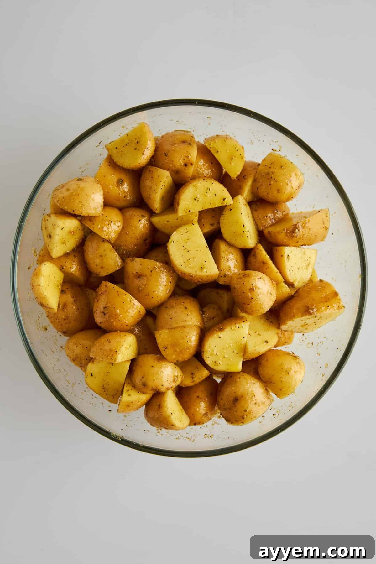 Seasoned golden potato pieces in a mixing bowl. 