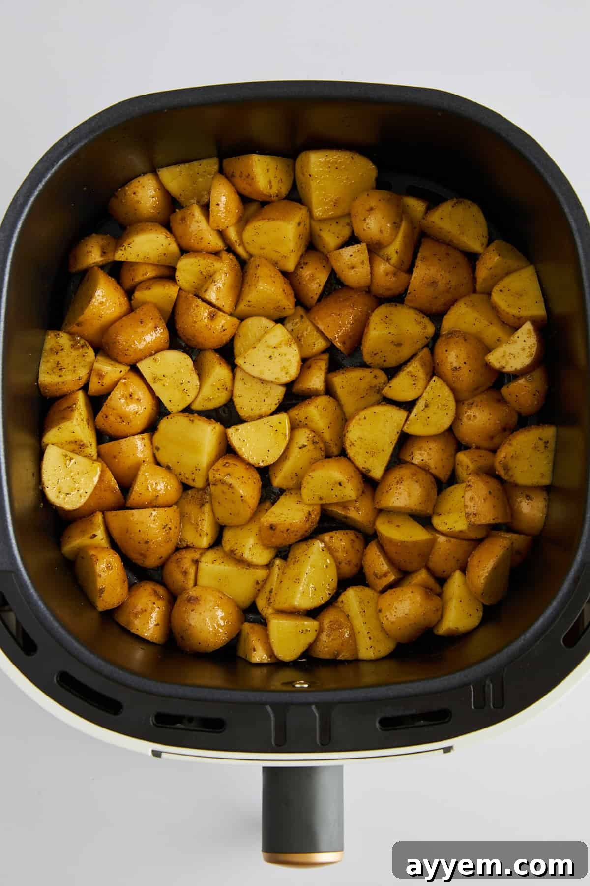 Uncooked Greek potatoes in an air fryer. 
