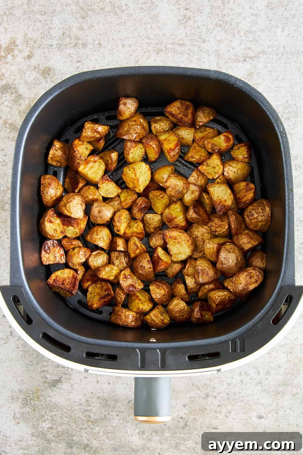 Cooked Greek potatoes in an air fryer basket. 