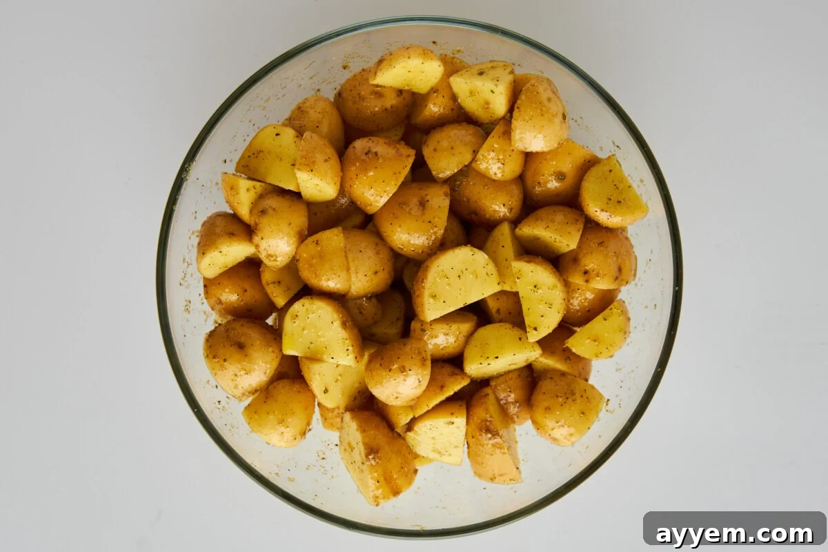 Seasoned Greek potatoes in a mixing bowl.