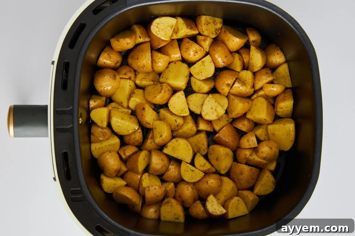 Uncooked Greek potatoes in an air fryer basket.