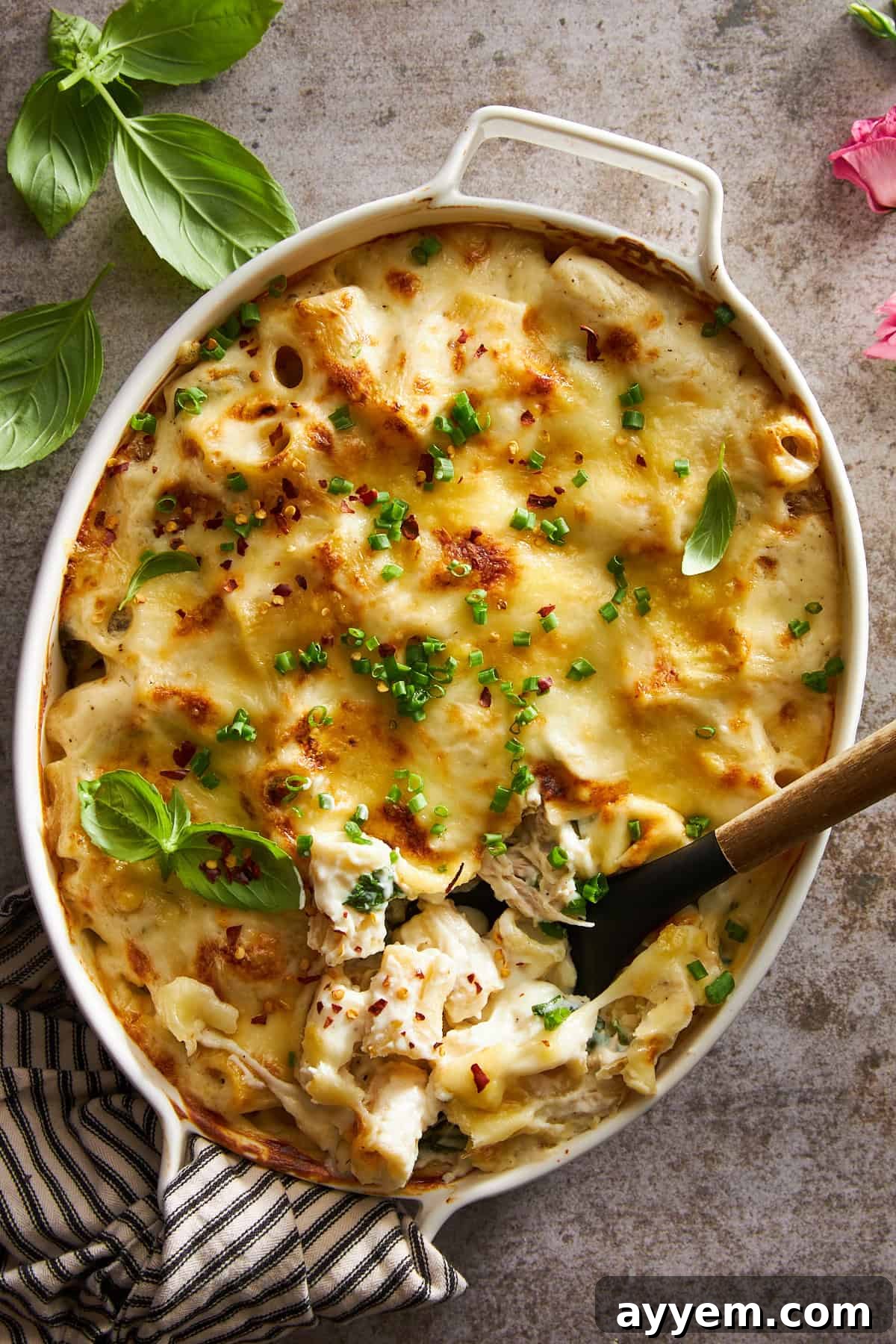 Overhead image of a chicken spinach pasta bake with a spoon sunk in, showcasing melted cheese and vibrant green spinach.