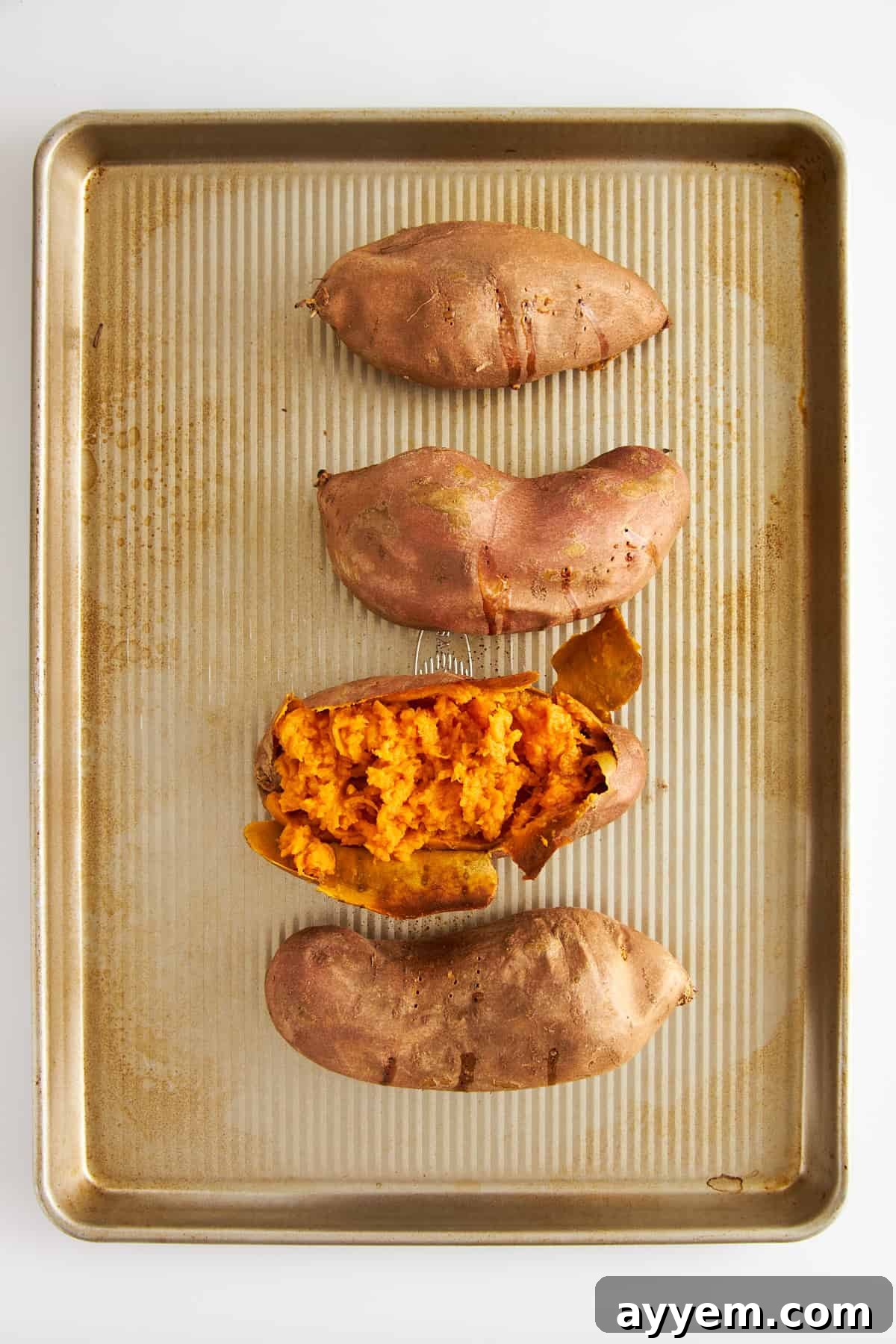 Creamy Dairy-Free Sweet Potato Mash 4 Four baked sweet potatoes with one exposed to show the soft center.