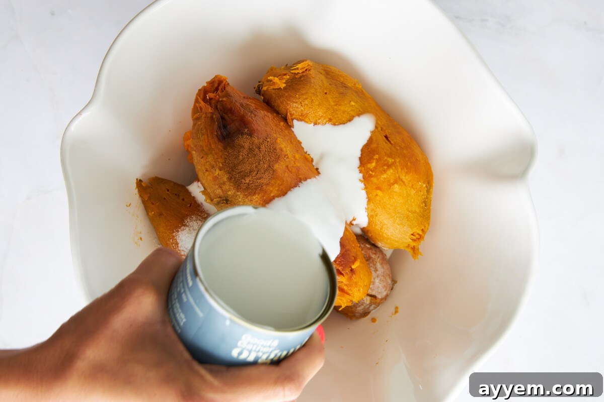 Coconut milk being poured over peeled sweet potatoes.