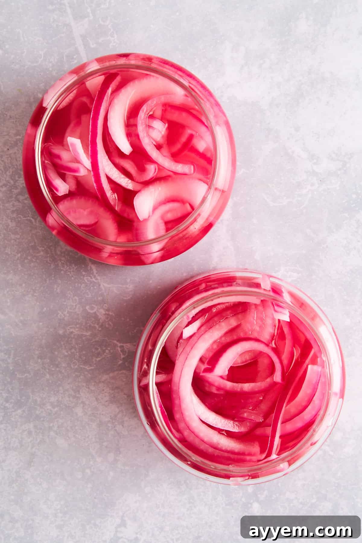 Overhead image of two jars of pickled red onions. 