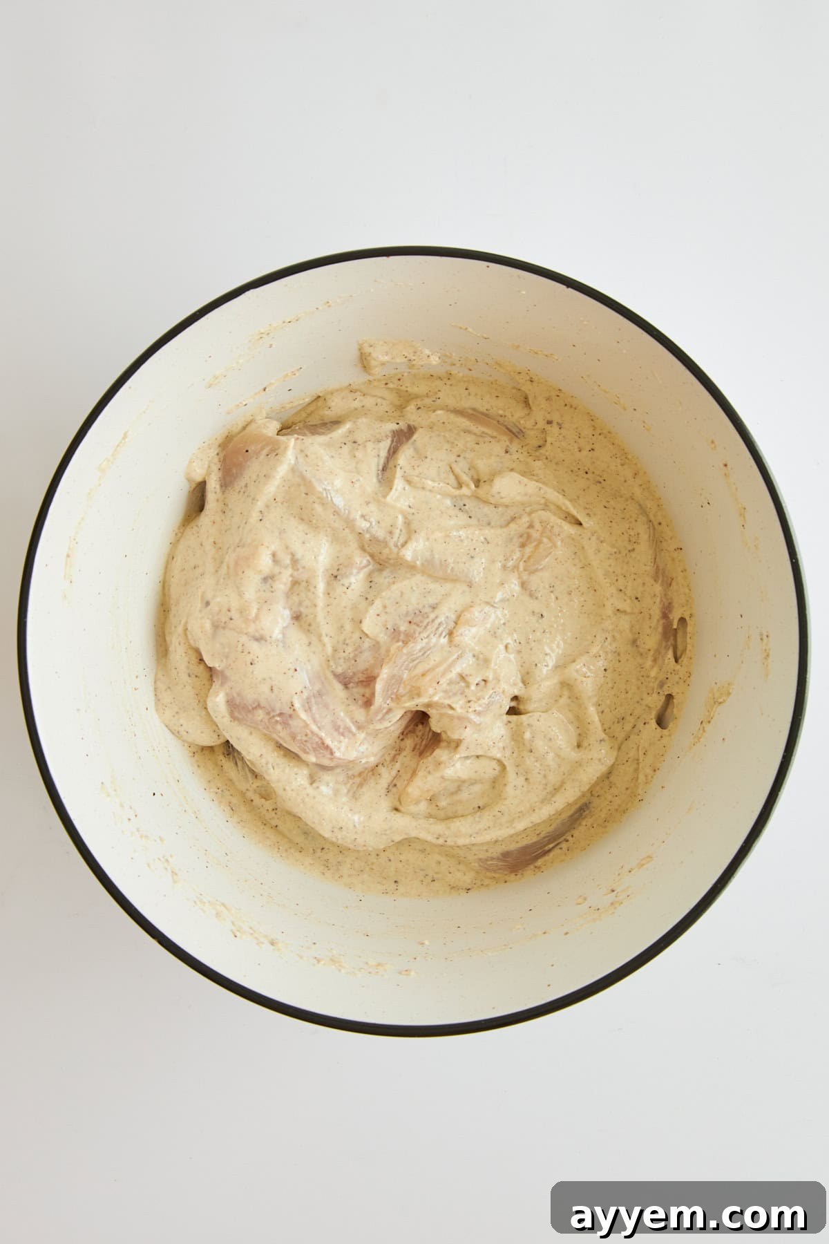 Chicken fully coated in tahini yogurt marinade, ready for marinating.