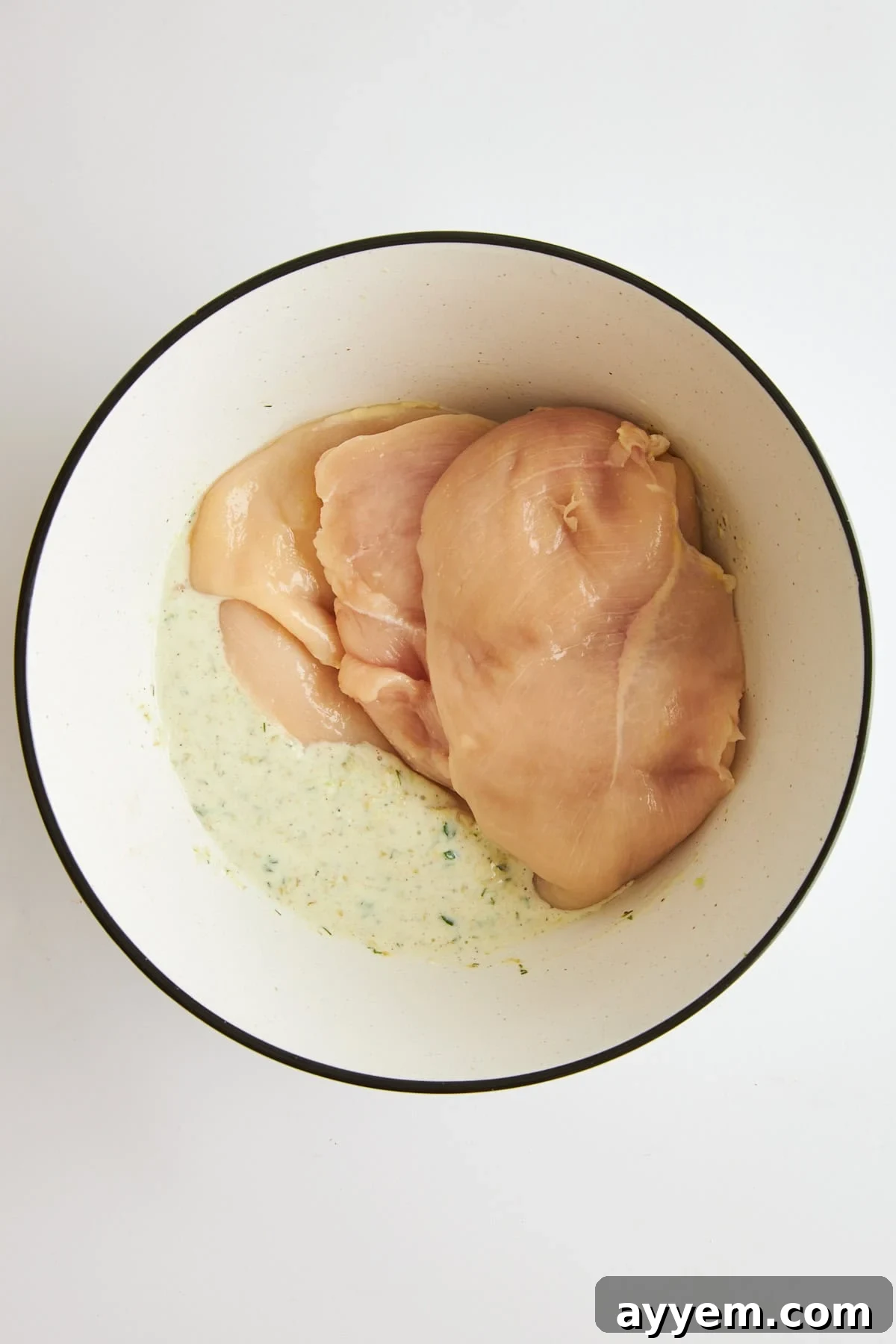 A bowl of tzatziki marinade ready to be mixed with raw chicken.