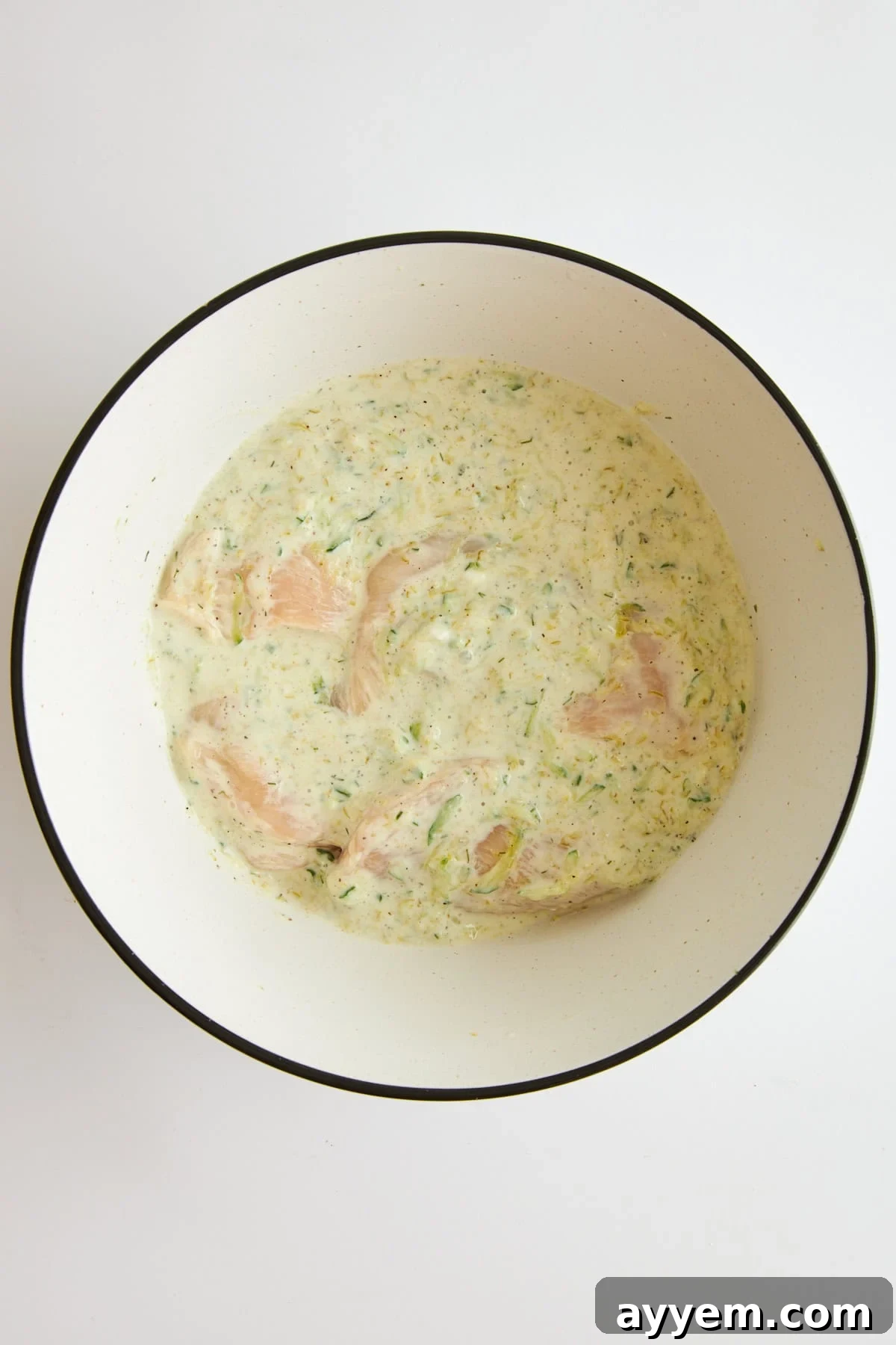 Raw chicken marinading in tzatziki chicken marinade, ready for refrigeration.
