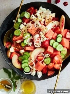 A vibrant bowl of watermelon cucumber salad with crumbled feta cheese and fresh mint leaves, perfect for summer.