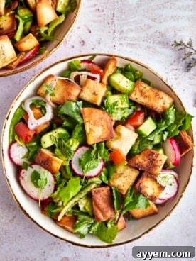 A beautifully presented Lebanese Fattoush salad, topped with crispy pita chips, vibrant vegetables, and a rich sumac dressing.
