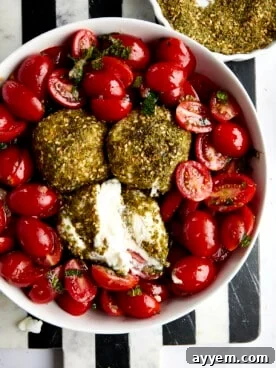 A close-up of a luxurious tomato and burrata salad, generously seasoned with fragrant za'atar and fresh basil.