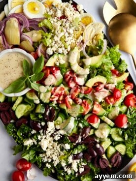 A beautifully arranged platter of Middle Eastern Cobb Salad, featuring distinct rows of ingredients and a dressing on the side.