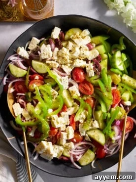 A classic, rustic bowl of Greek salad, brimming with fresh vegetables, olives, and a generous block of feta cheese.