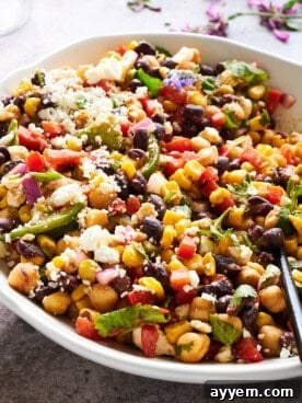 A large, inviting bowl of black bean and corn salad, garnished with fresh cilantro and vibrant red onions.