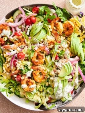 A bowl of fresh shrimp avocado salad with crisp greens, juicy tomatoes, and a creamy tahini dressing.