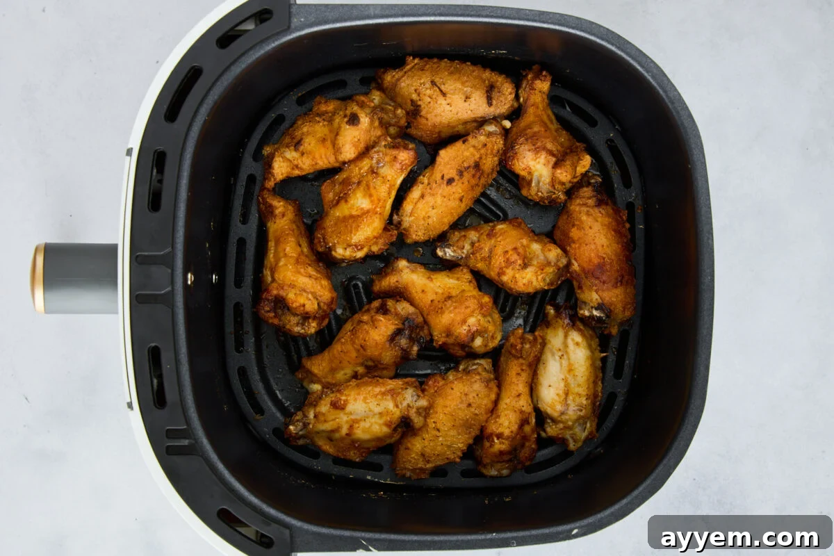 Cooked parmesan garlic chicken wings in an air fryer basket.