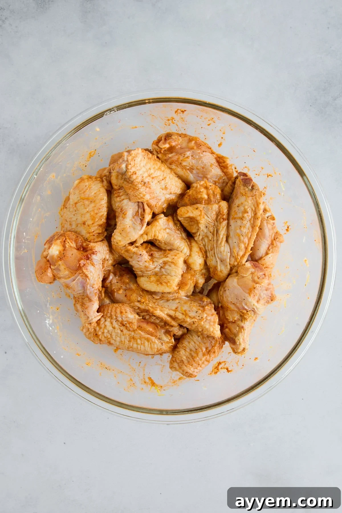 Close-up of raw chicken wings, thoroughly coated with a flavorful spice mixture.