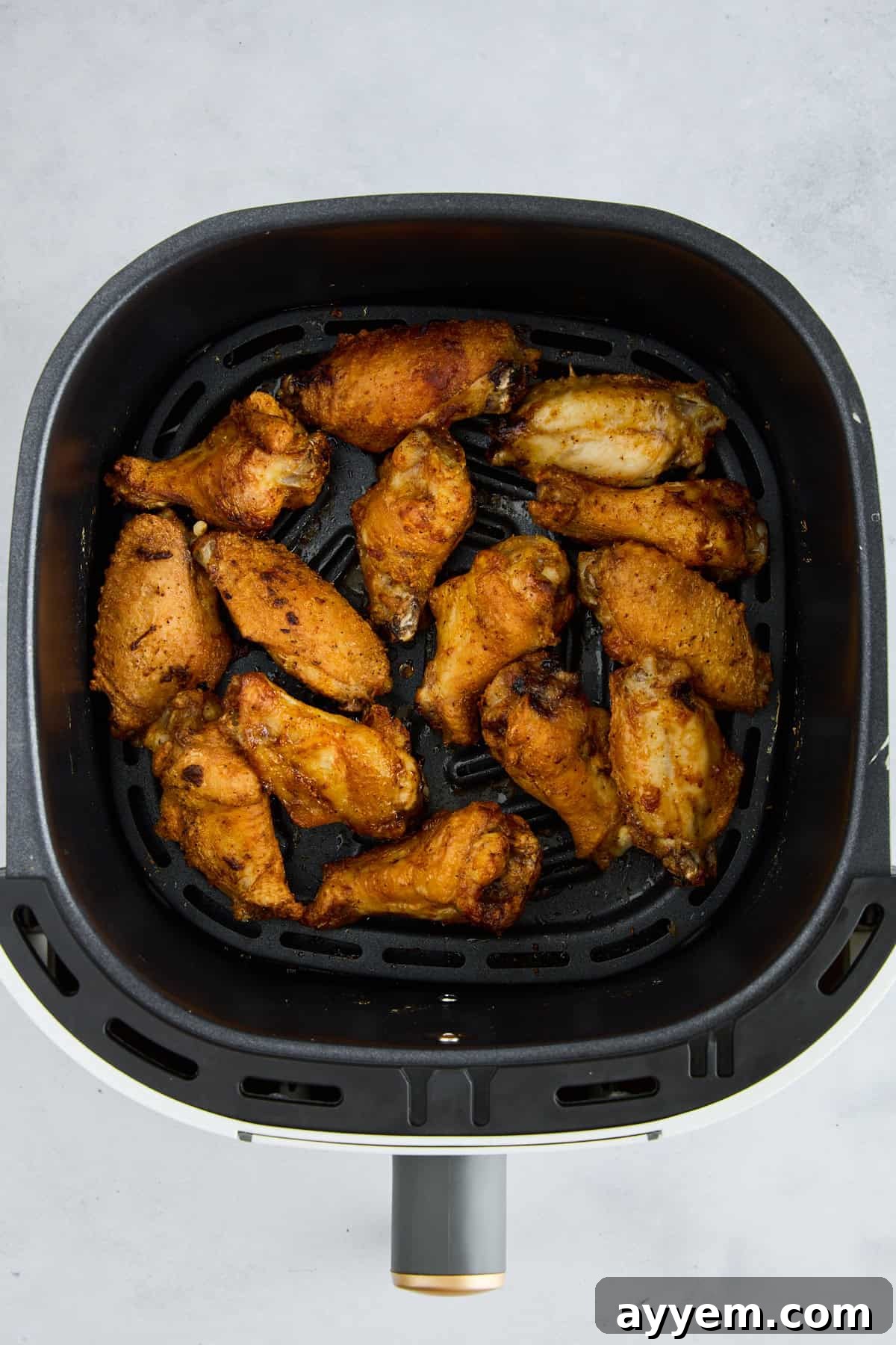 Perfectly cooked Air Fryer Garlic Parmesan Chicken Wings, golden and crispy, inside an air fryer basket.