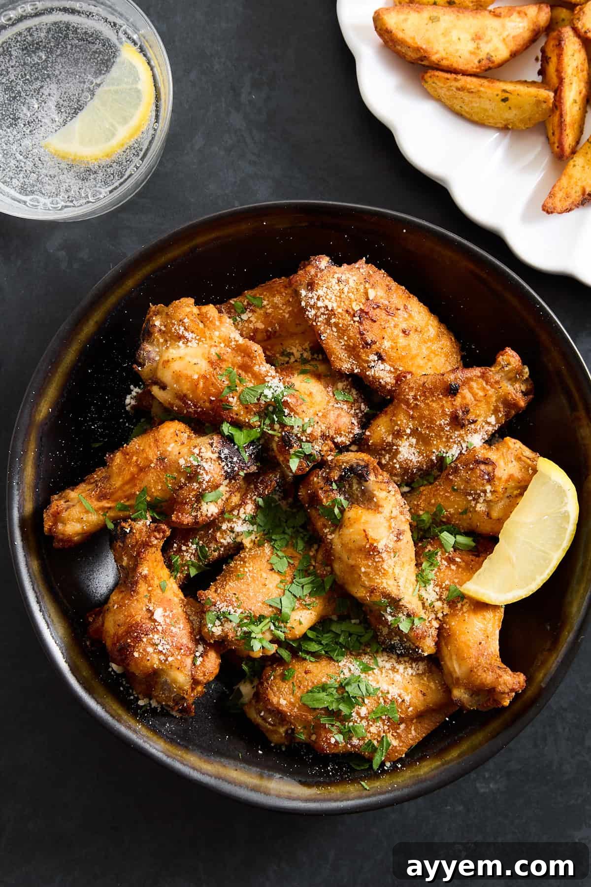 A bowl of parmesan garlic chicken wings, garnished with fresh parsley.