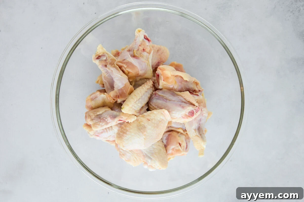 Raw chicken wings in a glass bowl.