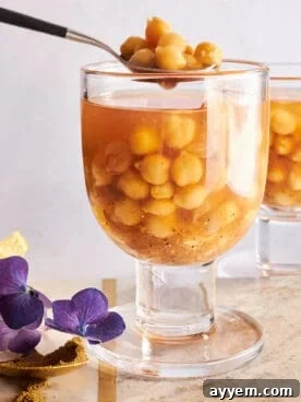 A warm cup of Hummus el Sham, a spiced chickpea soup, garnished with fresh herbs and a slice of lemon.